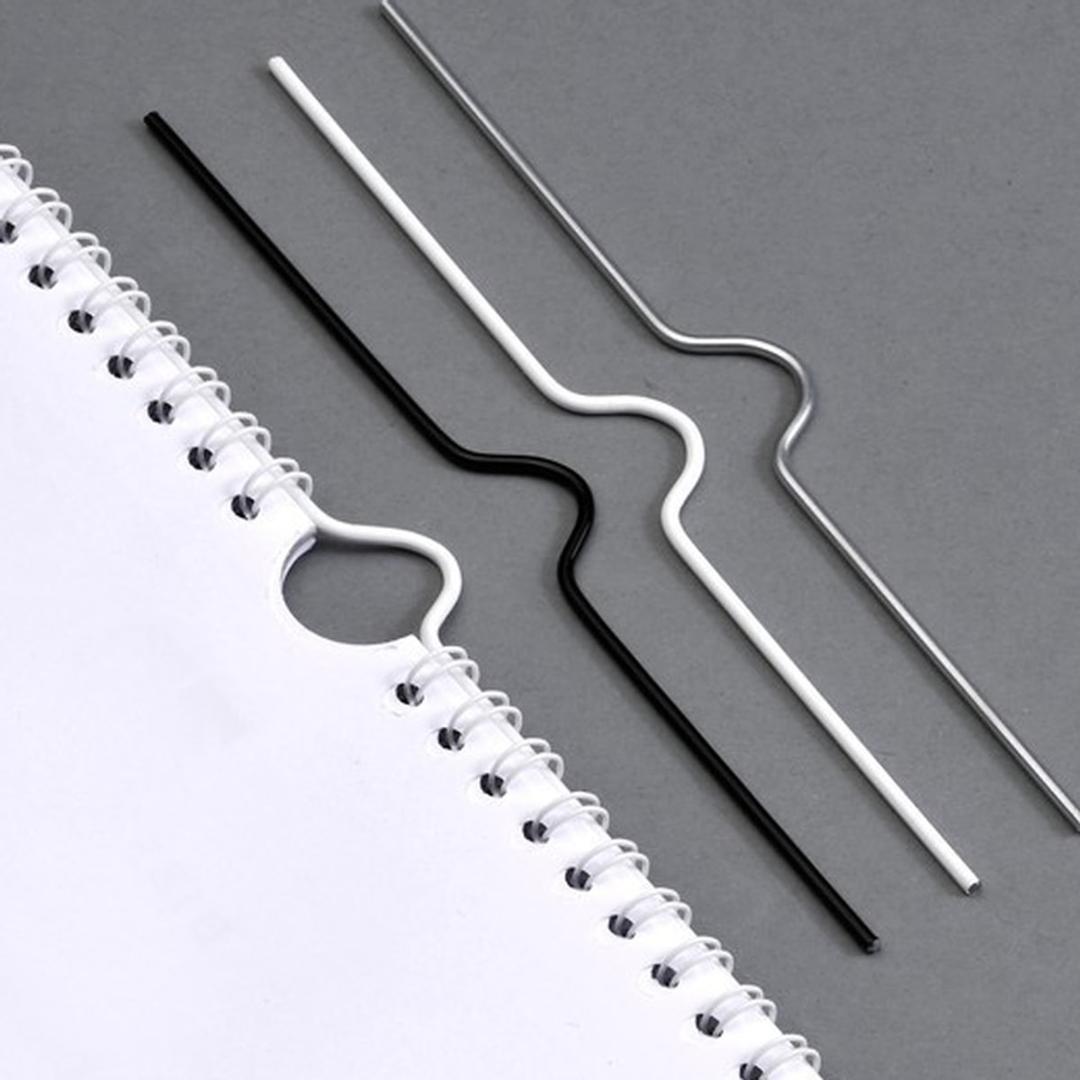 Crochets de calendrier noir, blanc et argent, l'un passé dans l'encoche demi-lune d'un calendrier relié en anneaux métalliques